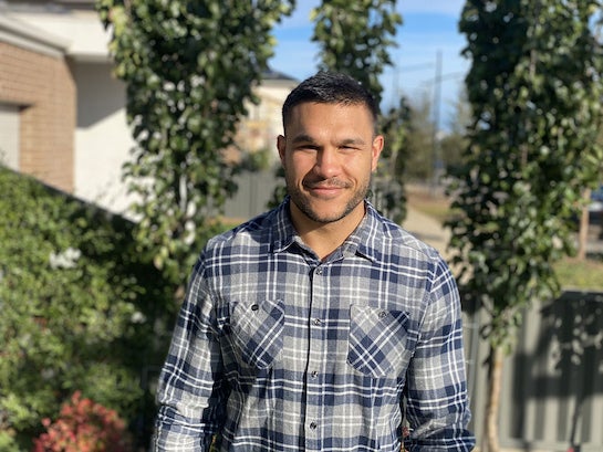 A portrait style photo of Josh, a man with dark hair and short facial hair, looking to camera and smiling. 