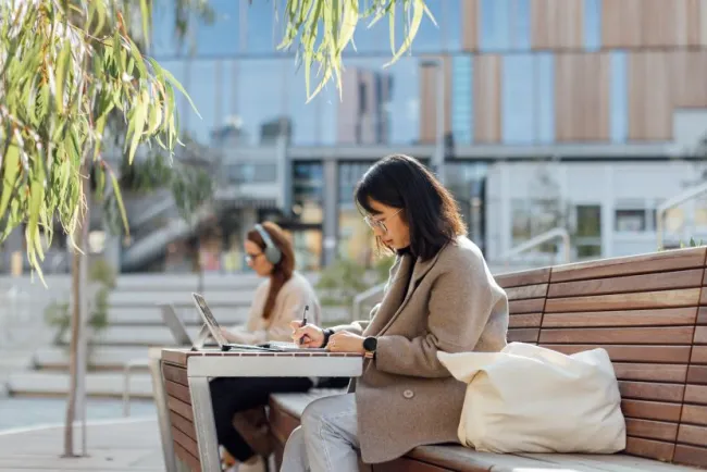 A student studying on their laptop in a student precinct or park.